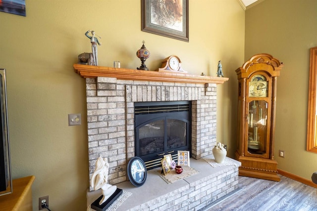 room details featuring a brick fireplace, wood finished floors, and baseboards