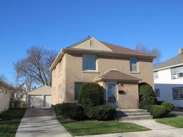 traditional-style house with a detached garage, brick siding, and an outdoor structure