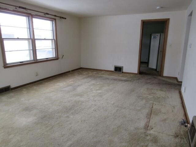 carpeted spare room with visible vents and baseboards