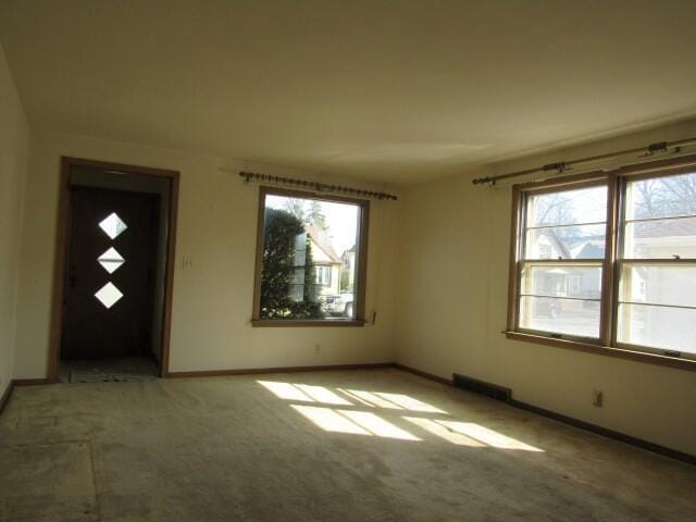 carpeted spare room with visible vents and baseboards