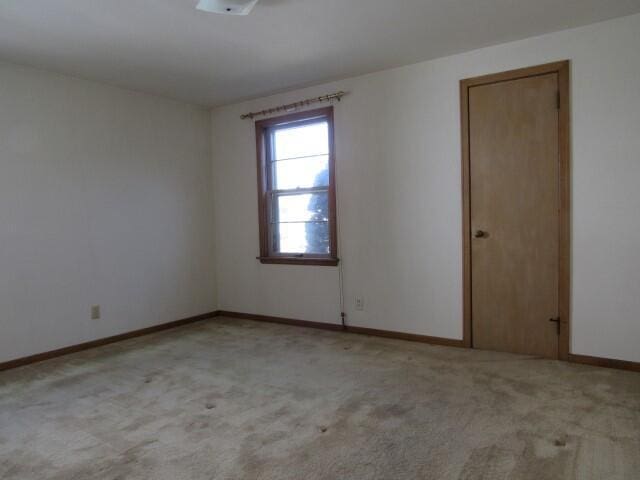 unfurnished room featuring baseboards and light carpet