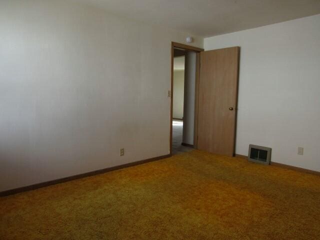 carpeted empty room featuring visible vents and baseboards