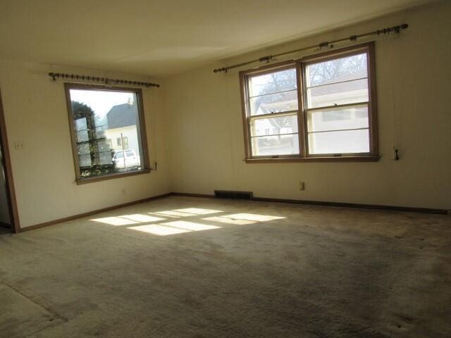 carpeted spare room with plenty of natural light, visible vents, and baseboards