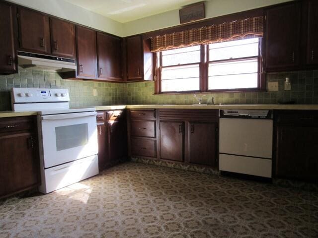 kitchen featuring tasteful backsplash, under cabinet range hood, light floors, light countertops, and white appliances