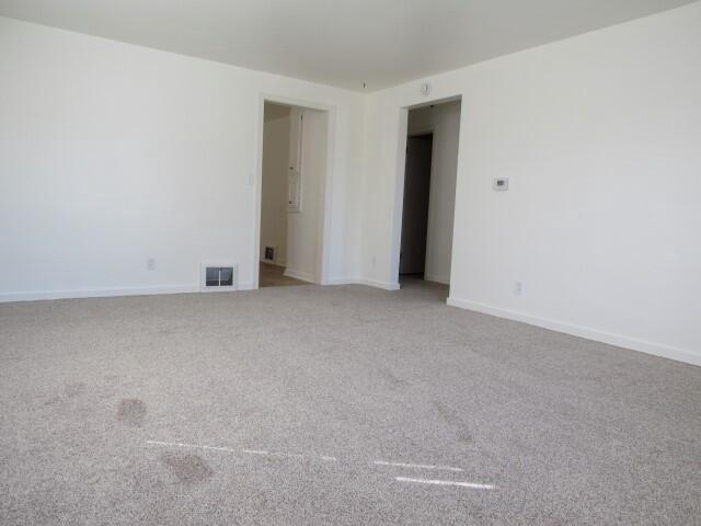 spare room with light carpet, visible vents, and baseboards