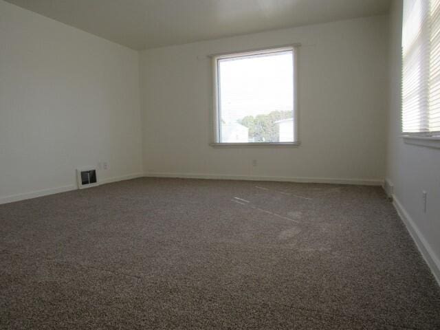 carpeted empty room with visible vents and baseboards