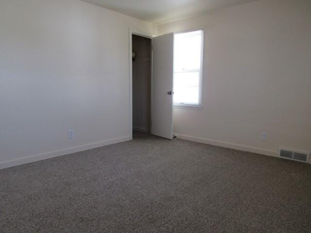 spare room featuring baseboards, visible vents, and light carpet