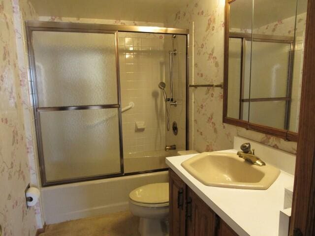 bathroom with enclosed tub / shower combo, toilet, vanity, and wallpapered walls