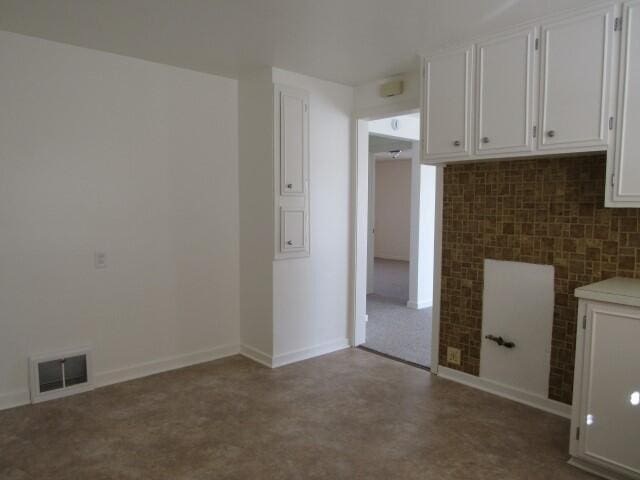 interior space featuring white cabinetry, light countertops, visible vents, and concrete floors