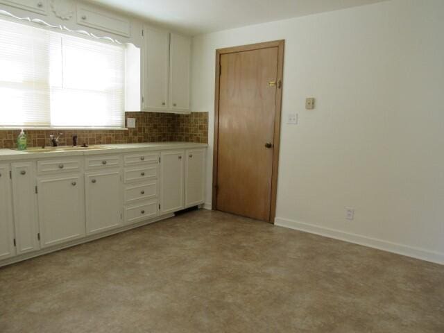 kitchen with backsplash, white cabinetry, and baseboards