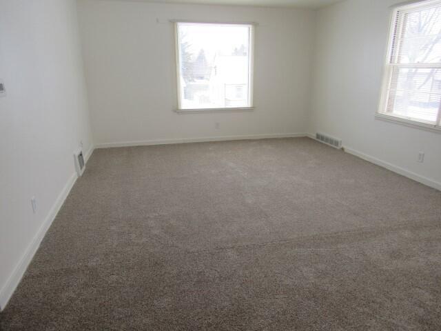 empty room with visible vents, baseboards, and carpet