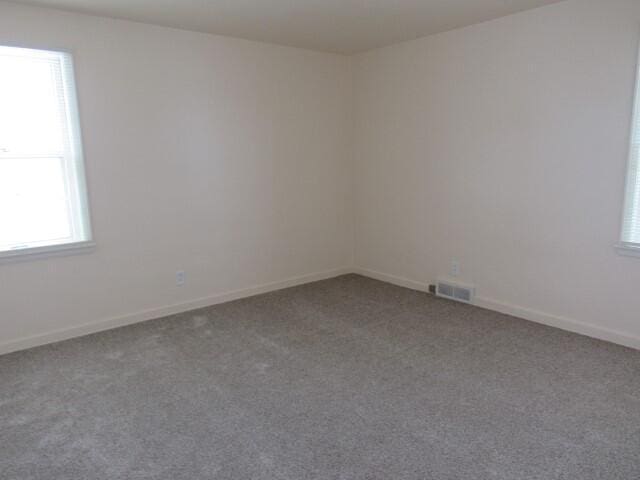 carpeted empty room with visible vents and baseboards