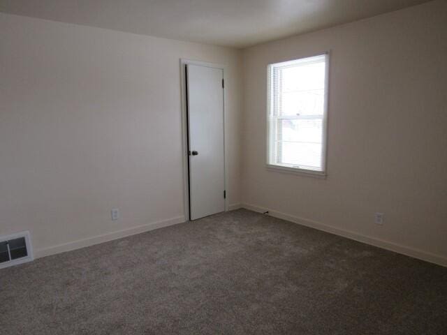 carpeted empty room featuring baseboards and visible vents