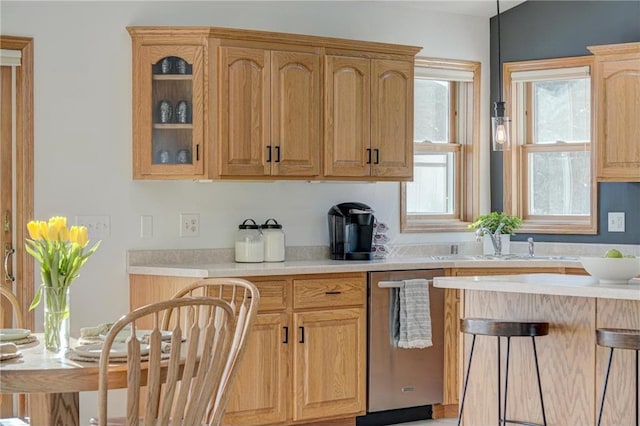 kitchen featuring a sink, a kitchen breakfast bar, light countertops, glass insert cabinets, and dishwasher