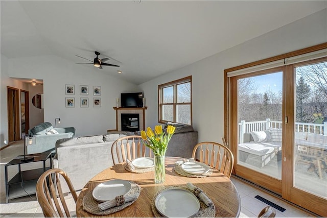 dining room with a tiled fireplace, lofted ceiling, plenty of natural light, and visible vents