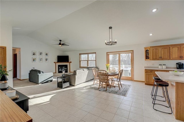 dining room featuring vaulted ceiling, light tile patterned floors, ceiling fan with notable chandelier, recessed lighting, and a glass covered fireplace