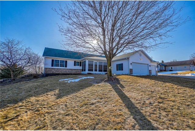 ranch-style home featuring a garage, stone siding, a front yard, and a sunroom