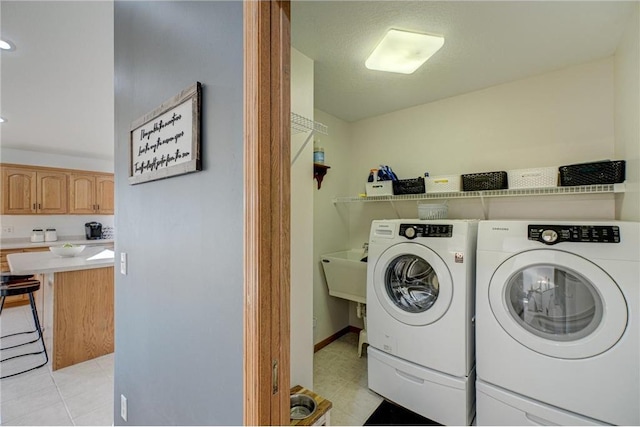 laundry room with laundry area, light tile patterned floors, independent washer and dryer, and a sink