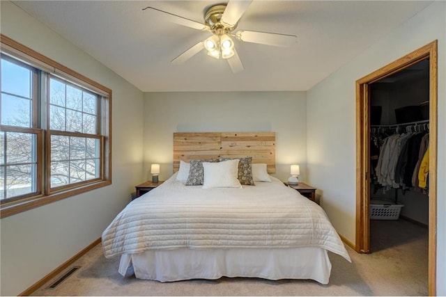 bedroom featuring a walk in closet, baseboards, visible vents, and carpet floors