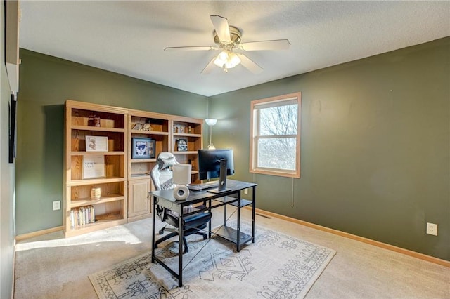 home office with a ceiling fan, baseboards, and light carpet