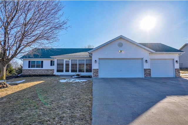 ranch-style home with a front yard, concrete driveway, a garage, and a sunroom