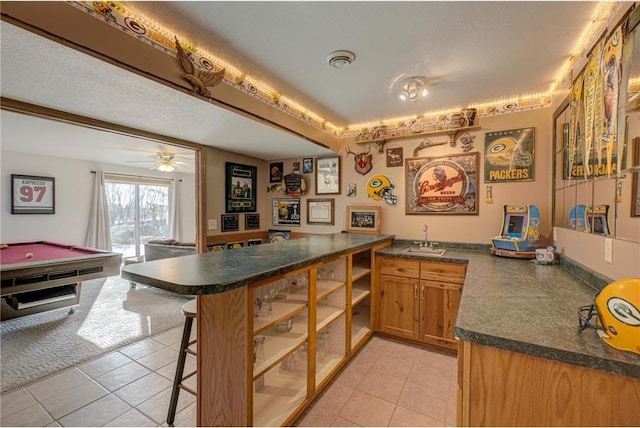 kitchen featuring a sink, a kitchen breakfast bar, dark countertops, and a peninsula