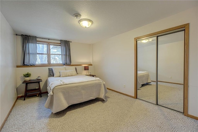 bedroom with a closet, a textured ceiling, baseboards, and carpet floors