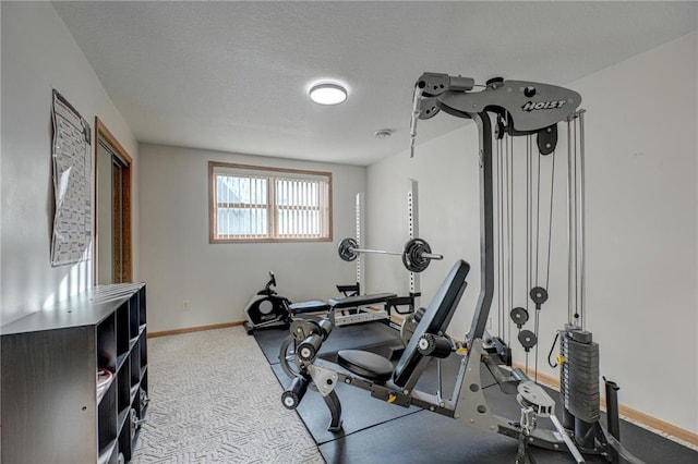 exercise area with baseboards, carpet floors, and a textured ceiling