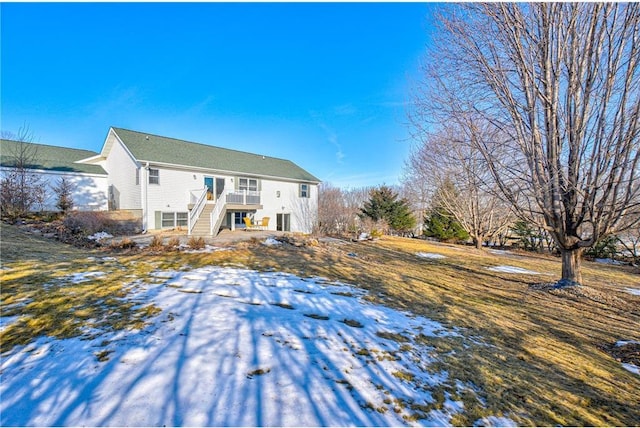 snow covered back of property with stairway and a deck