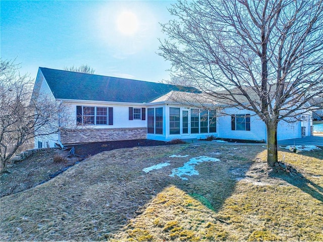 back of property with brick siding, a shingled roof, and a sunroom