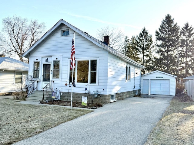 bungalow-style house featuring an outbuilding, a garage, driveway, and a chimney