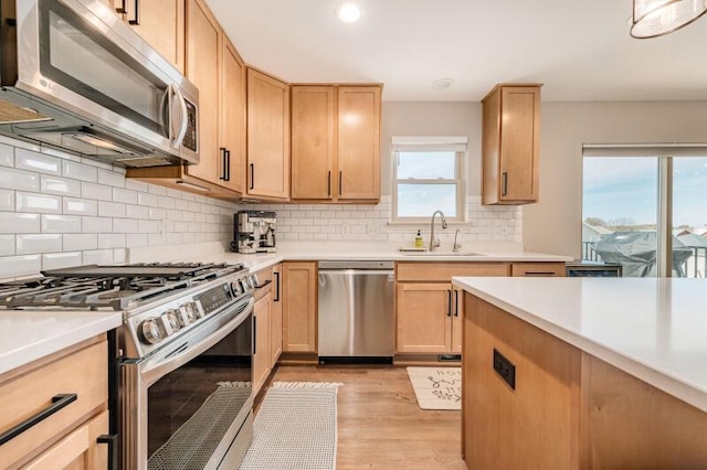 kitchen featuring light brown cabinetry, light countertops, appliances with stainless steel finishes, and a sink