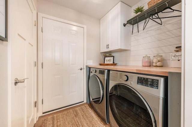 laundry area featuring light tile patterned floors, cabinet space, and separate washer and dryer