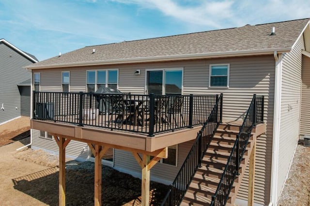 rear view of property featuring stairs, a deck, and a shingled roof