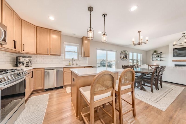 kitchen featuring light brown cabinetry, decorative backsplash, light countertops, stainless steel appliances, and open floor plan