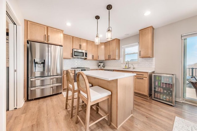 kitchen featuring light brown cabinetry, a sink, stainless steel appliances, wine cooler, and light wood finished floors