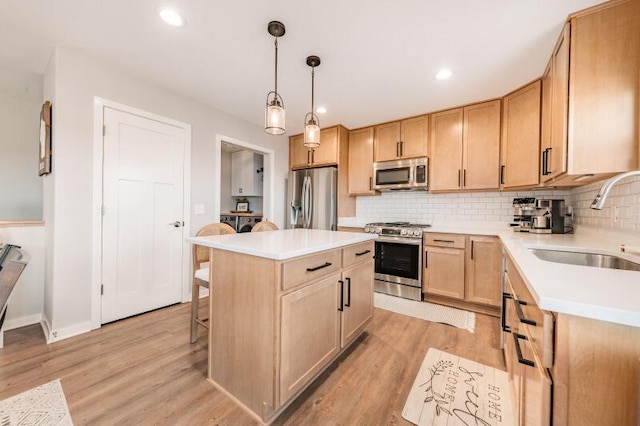 kitchen with light brown cabinets, appliances with stainless steel finishes, light wood-style floors, and a sink