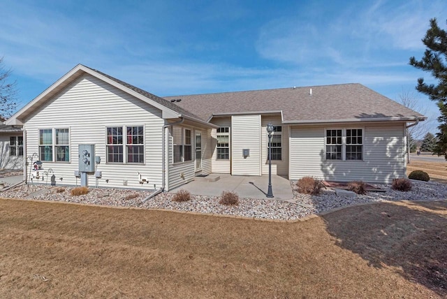 view of front of house featuring a patio area, a shingled roof, and a front yard