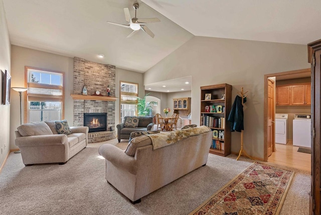 living area with washer and dryer, a fireplace, a wealth of natural light, and high vaulted ceiling