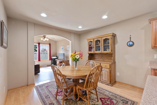 dining space with recessed lighting, baseboards, arched walkways, and light wood finished floors