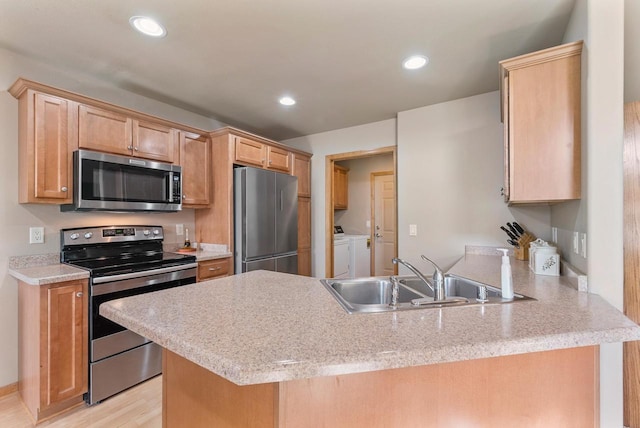 kitchen with washer and clothes dryer, a sink, recessed lighting, appliances with stainless steel finishes, and a peninsula