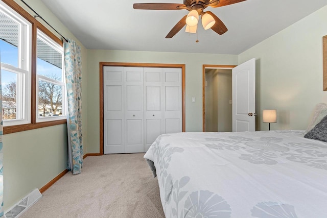 bedroom with visible vents, baseboards, ceiling fan, light colored carpet, and a closet