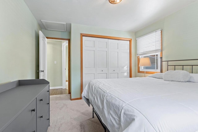 bedroom with attic access, light colored carpet, a closet, and baseboards