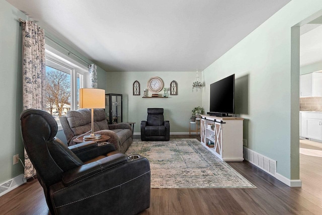 living area featuring visible vents, baseboards, and wood finished floors