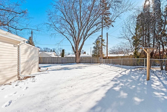 snowy yard with a fenced backyard