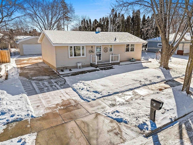 snow covered rear of property with a detached garage and an outdoor structure