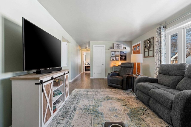 living area with vaulted ceiling, baseboards, and wood finished floors