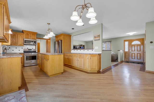 kitchen featuring backsplash, light countertops, light wood-style flooring, stainless steel appliances, and a sink