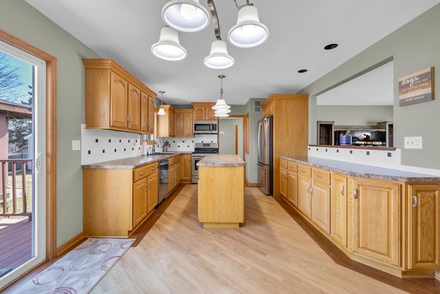 kitchen featuring light wood-type flooring, tasteful backsplash, a center island, stainless steel appliances, and light countertops