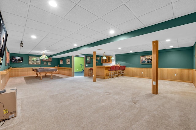 recreation room with recessed lighting, a wainscoted wall, a bar, and wood walls